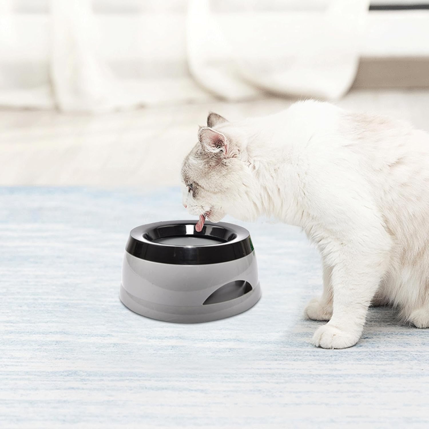 Cat drinking from a modern pet water fountain on a soft surface.