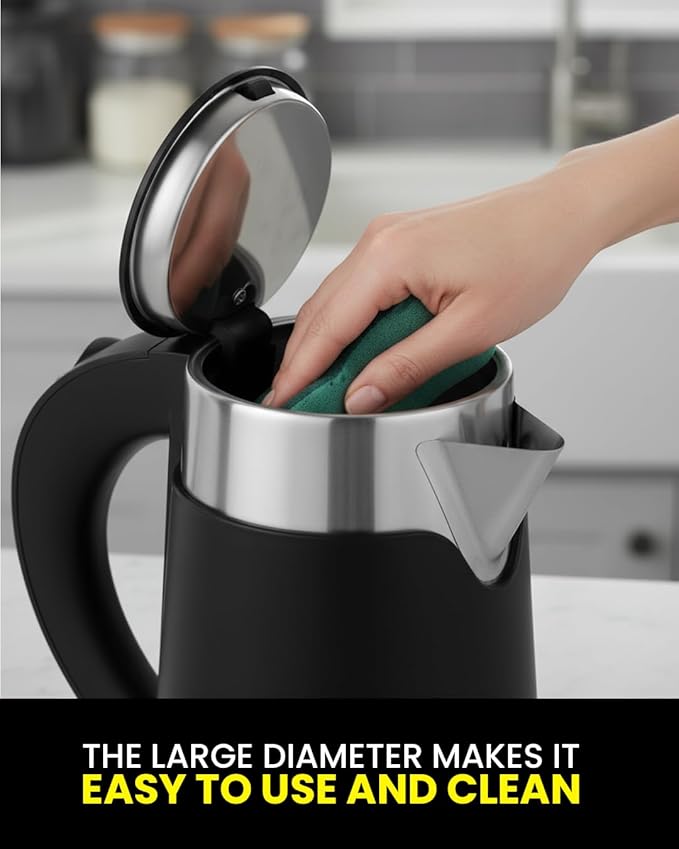 Person cleaning a black electric kettle with a green sponge in a kitchen setting.