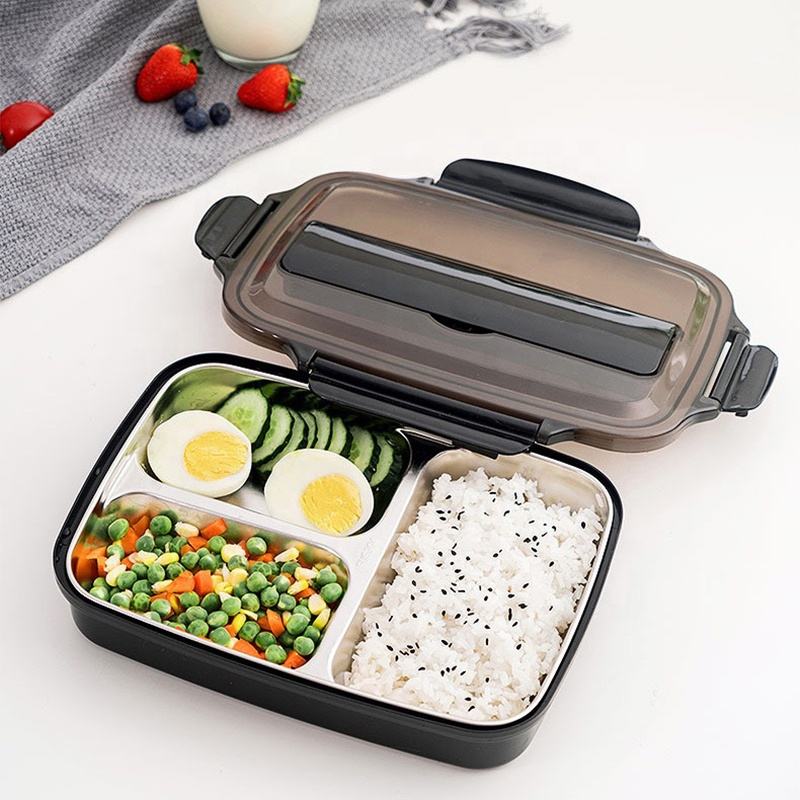 Bento box with compartments of rice, vegetables, and eggs on a white surface.