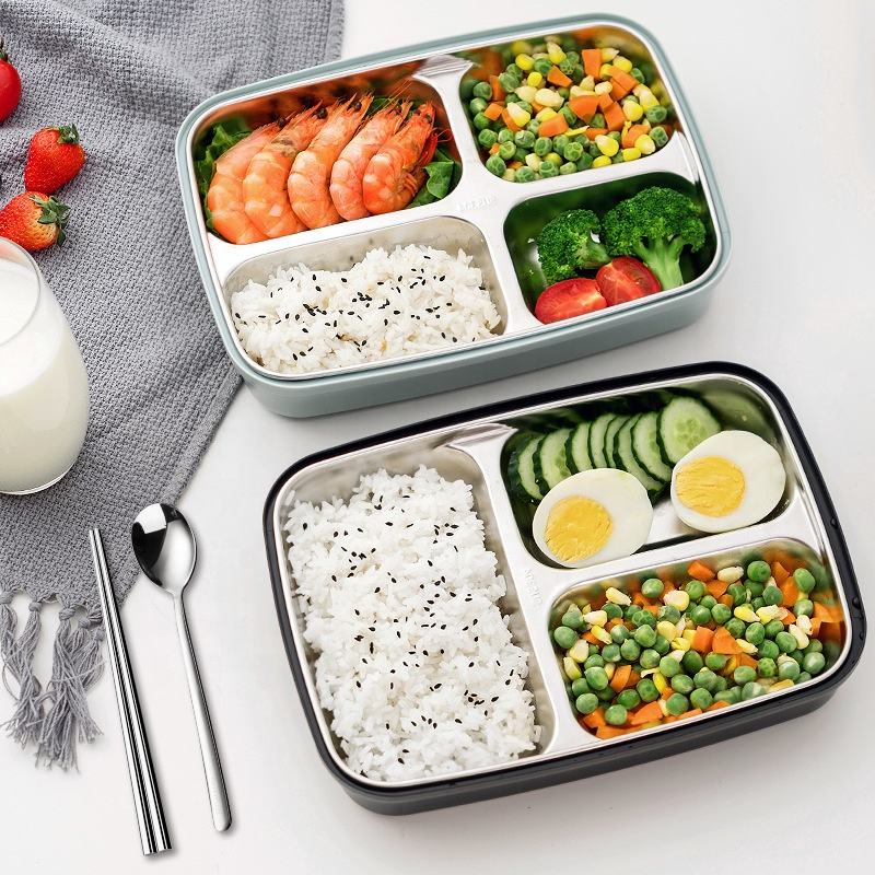 Two bento boxes with rice, vegetables, and other foods on a white surface.