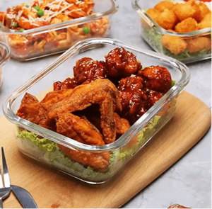 Glass containers with food on a wooden cutting board and gray surface