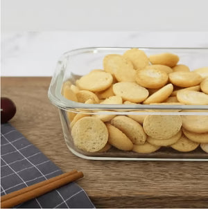 Glass container filled with round crackers on a wooden surface