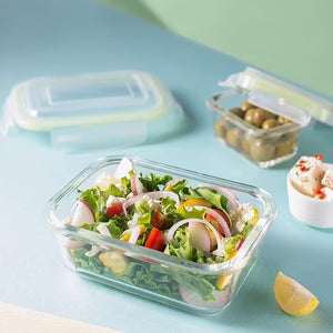 Glass salad container with a salad on a light blue surface
