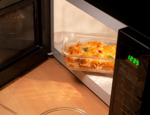 Microwave oven with a dish of food inside, showing the digital display.
